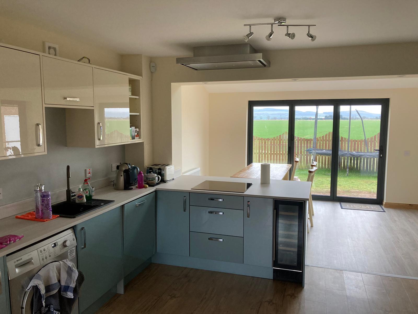 Teal kitchen with bifold doors and countryside views