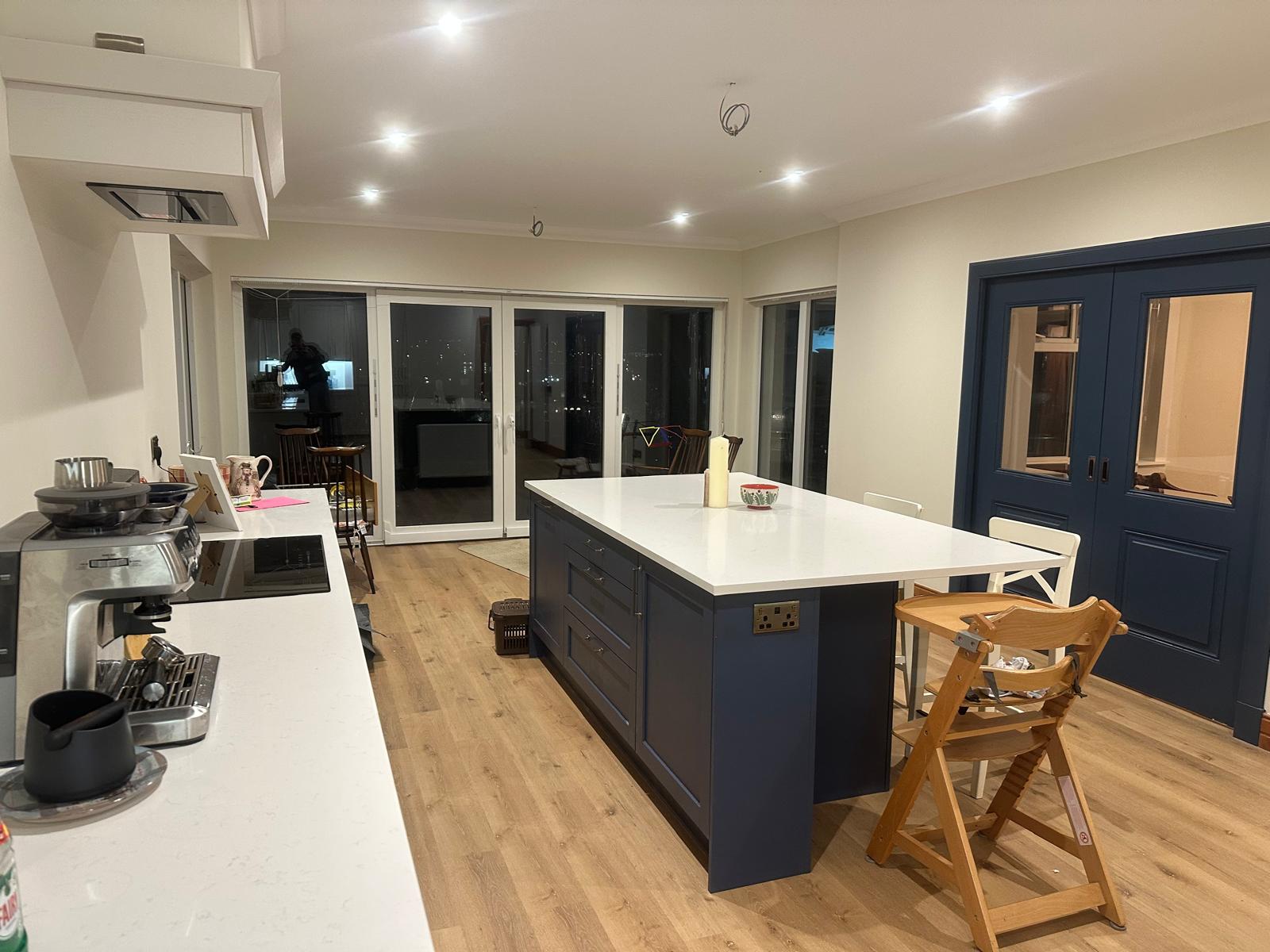 Navy blue kitchen with white island at night