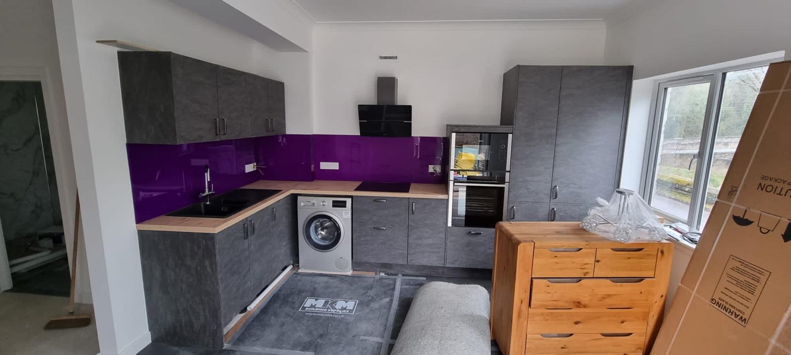 Purple splashback kitchen with dark units