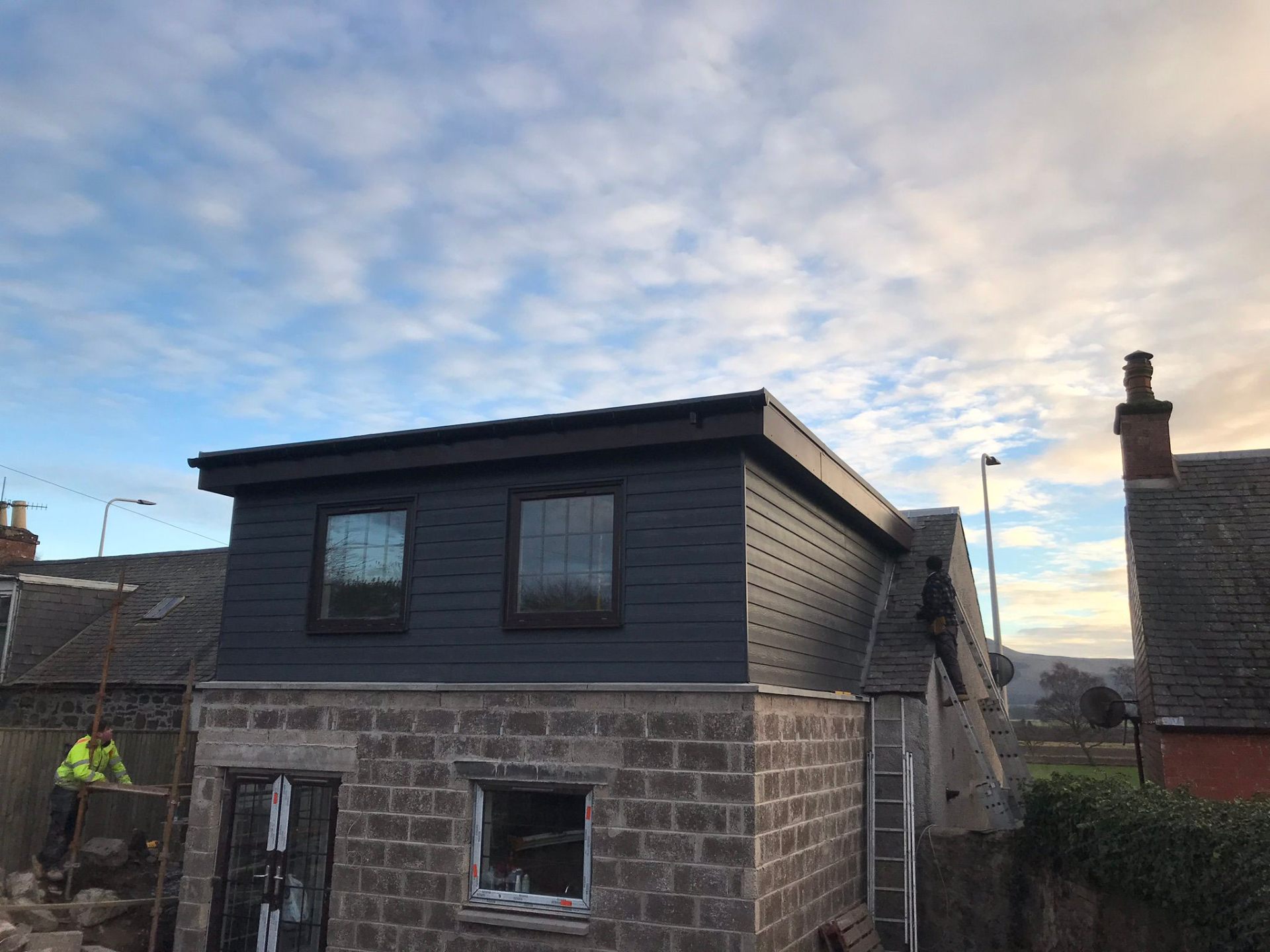 Two-storey extension with dark cladding dormer